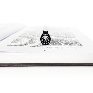Front view of black owl metal bookmark resting inside an open book, highlighting the detailed laser cut owl shape and glossy powder coated finish.