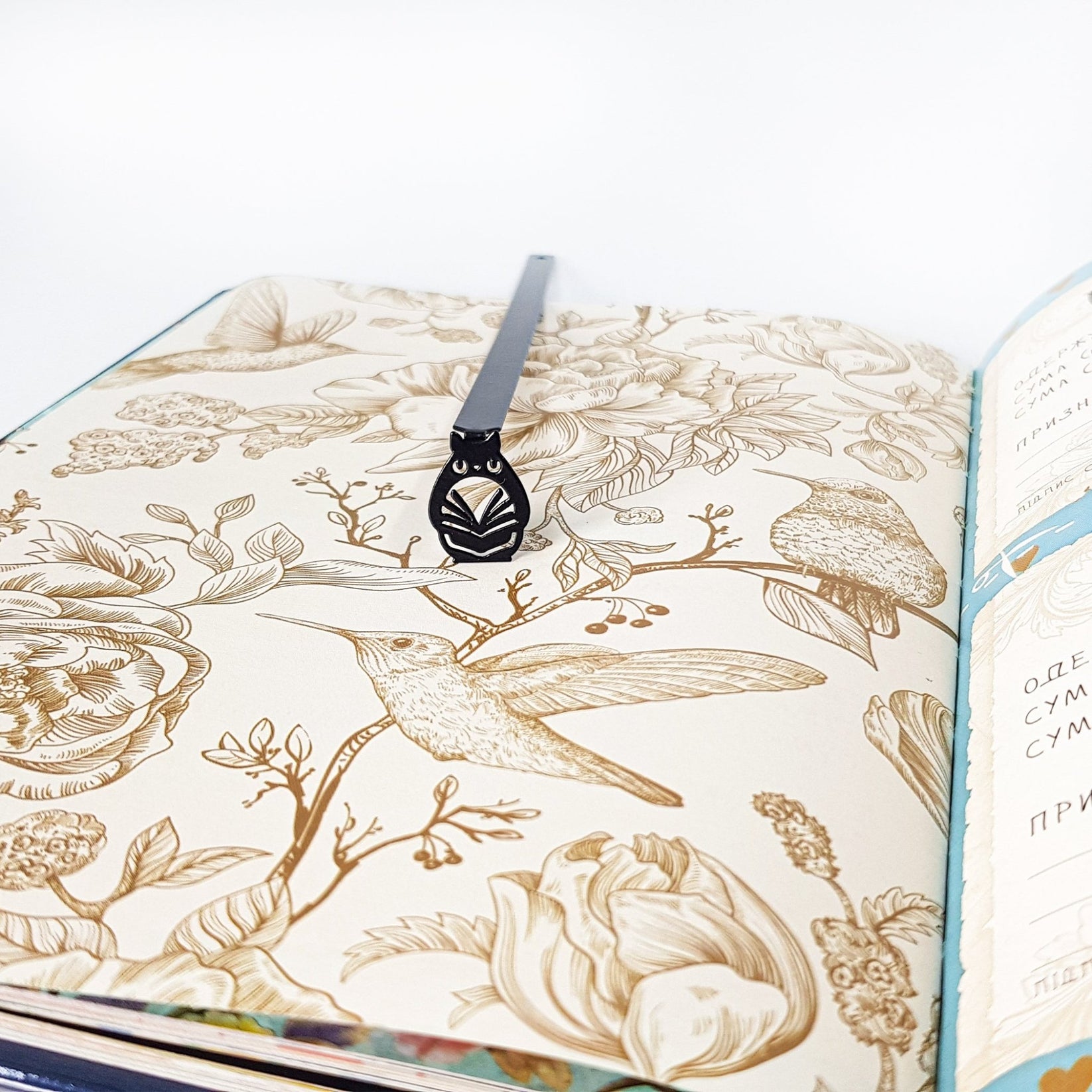 Laser Cut Metal Owl bookmark placed on a colour illustration