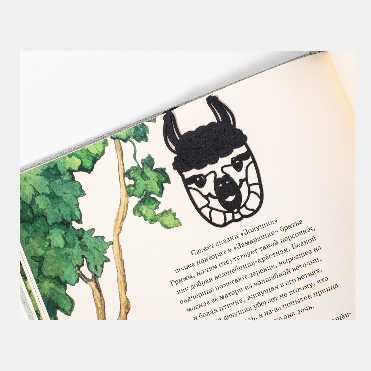Llama metal bookmark marking a page in an illustrated book