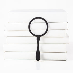 Magnifying Glass metal bookmark shown with a stack of books
