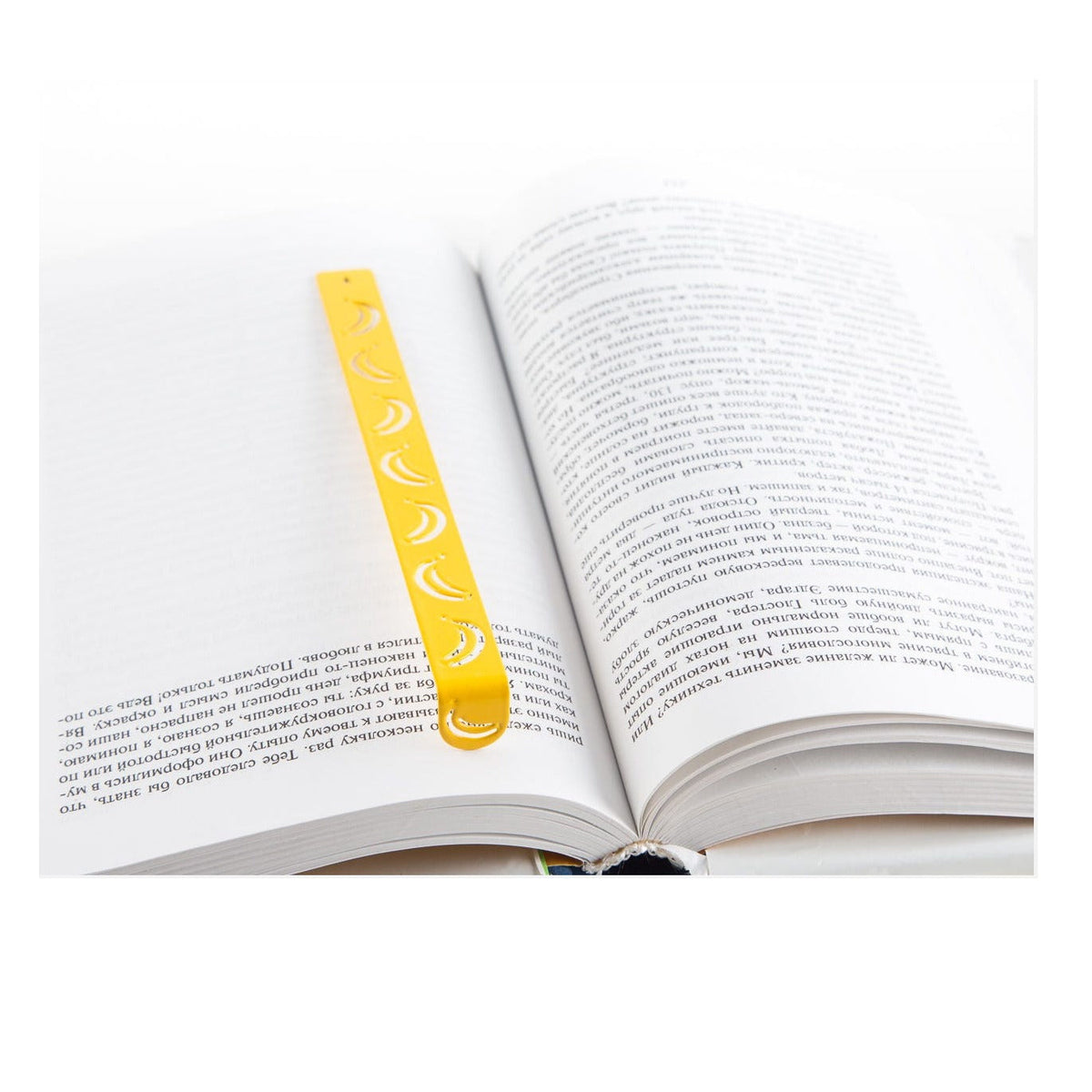 Many Bananas metal bookmark in gold resting on the pages of an open book