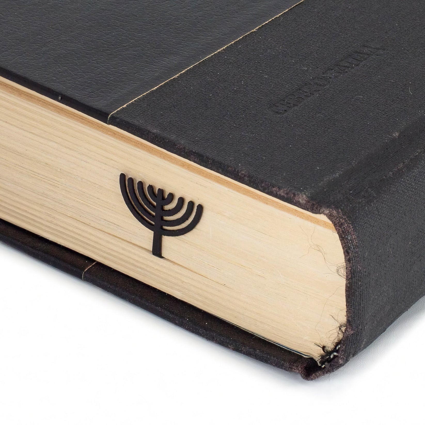 Menorah metal bookmark in a closed book, only its top showing above the pages
