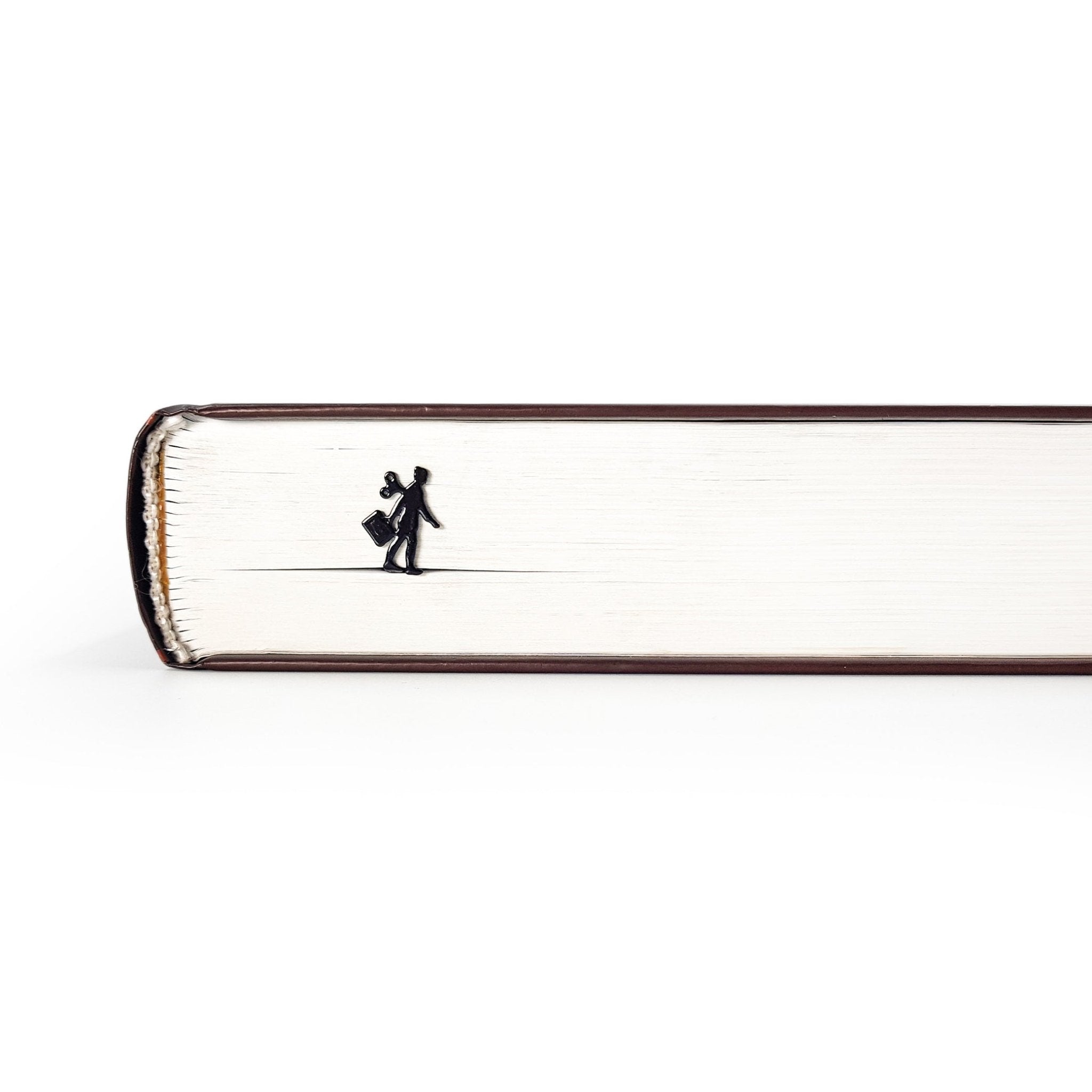 Black metal bookmark shaped like a walking businesswoman with a wind-up key, visible along the edge of a closed book.