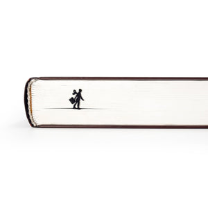 Black metal bookmark shaped like a walking businesswoman with a wind-up key, visible along the edge of a closed book.