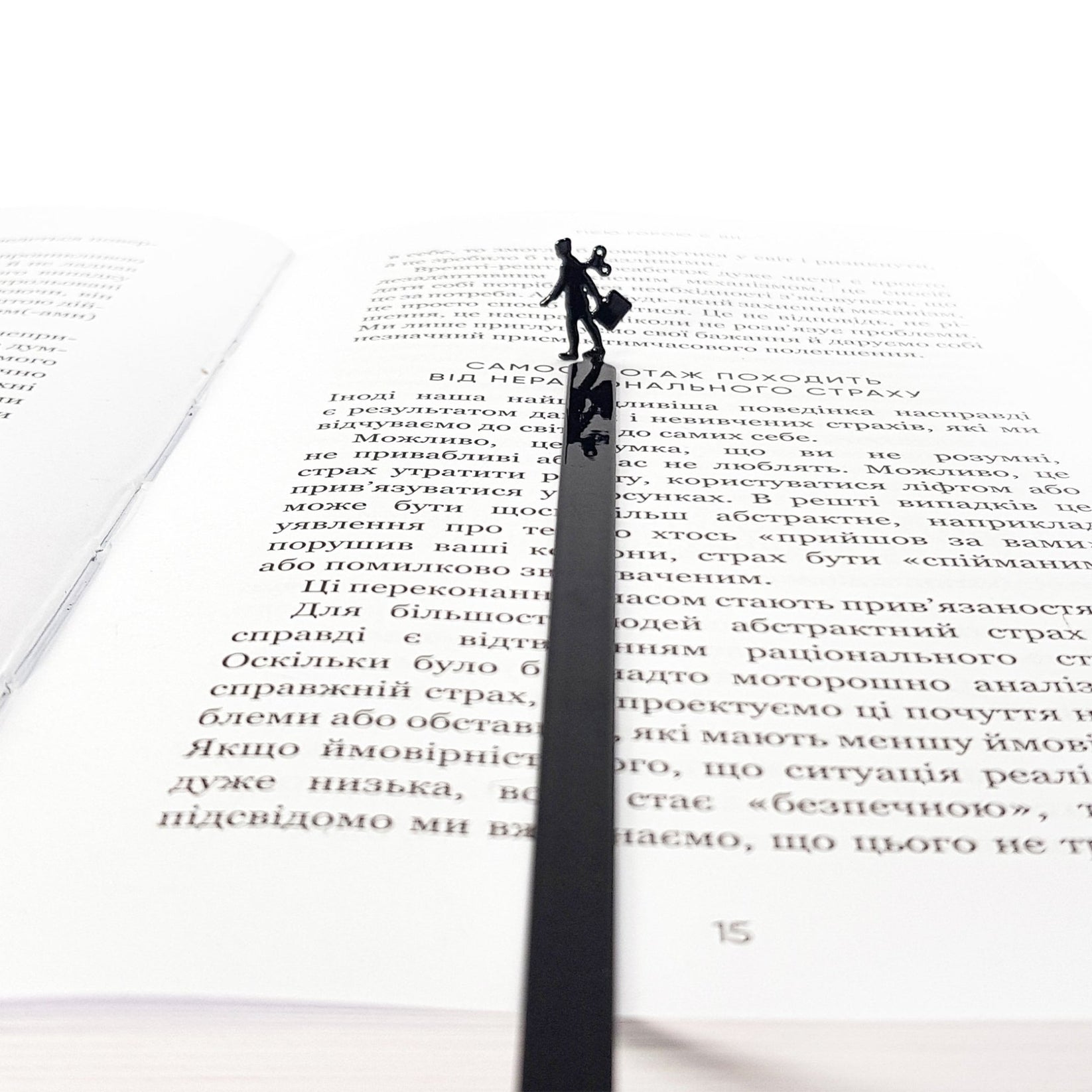 Black metal bookmark with a walking businesswoman silhouette placed inside an open book, minimalist reading accessory for modern readers.