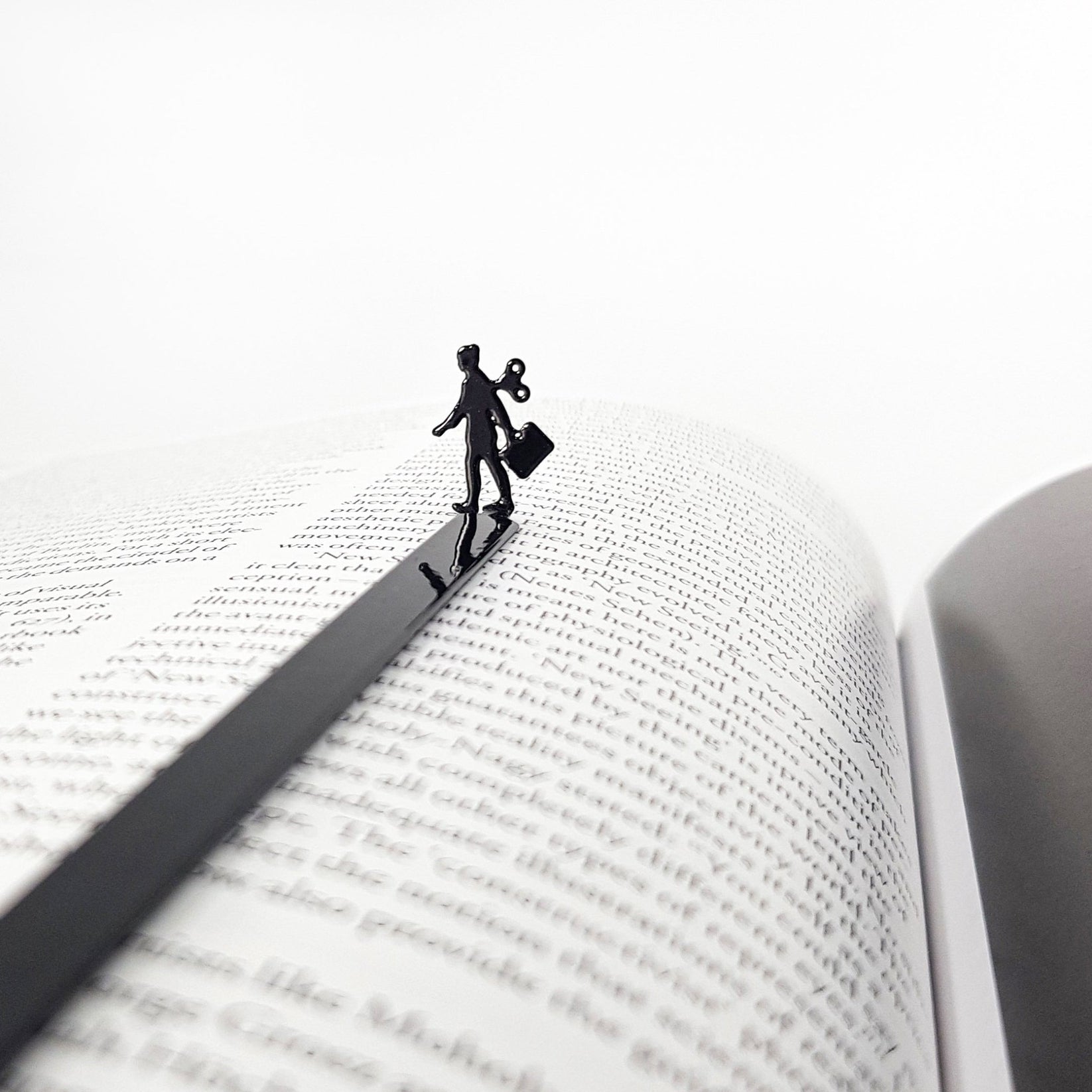 Black metal bookmark featuring a business woman silhouette with a wind up key resting on an open book page