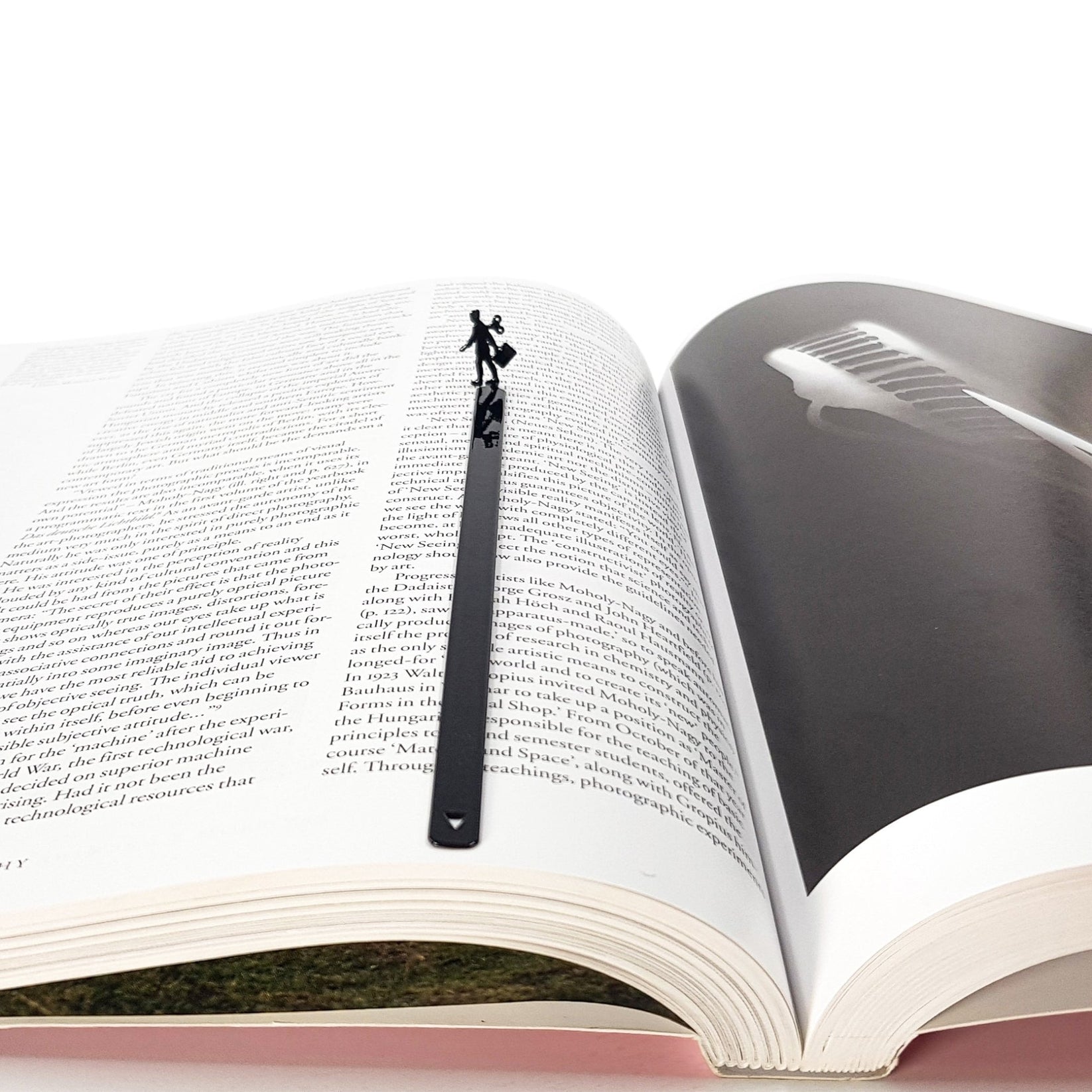 Black metal bookmark with a walking businesswoman silhouette centered in an open book, minimalist handmade reading accessory.