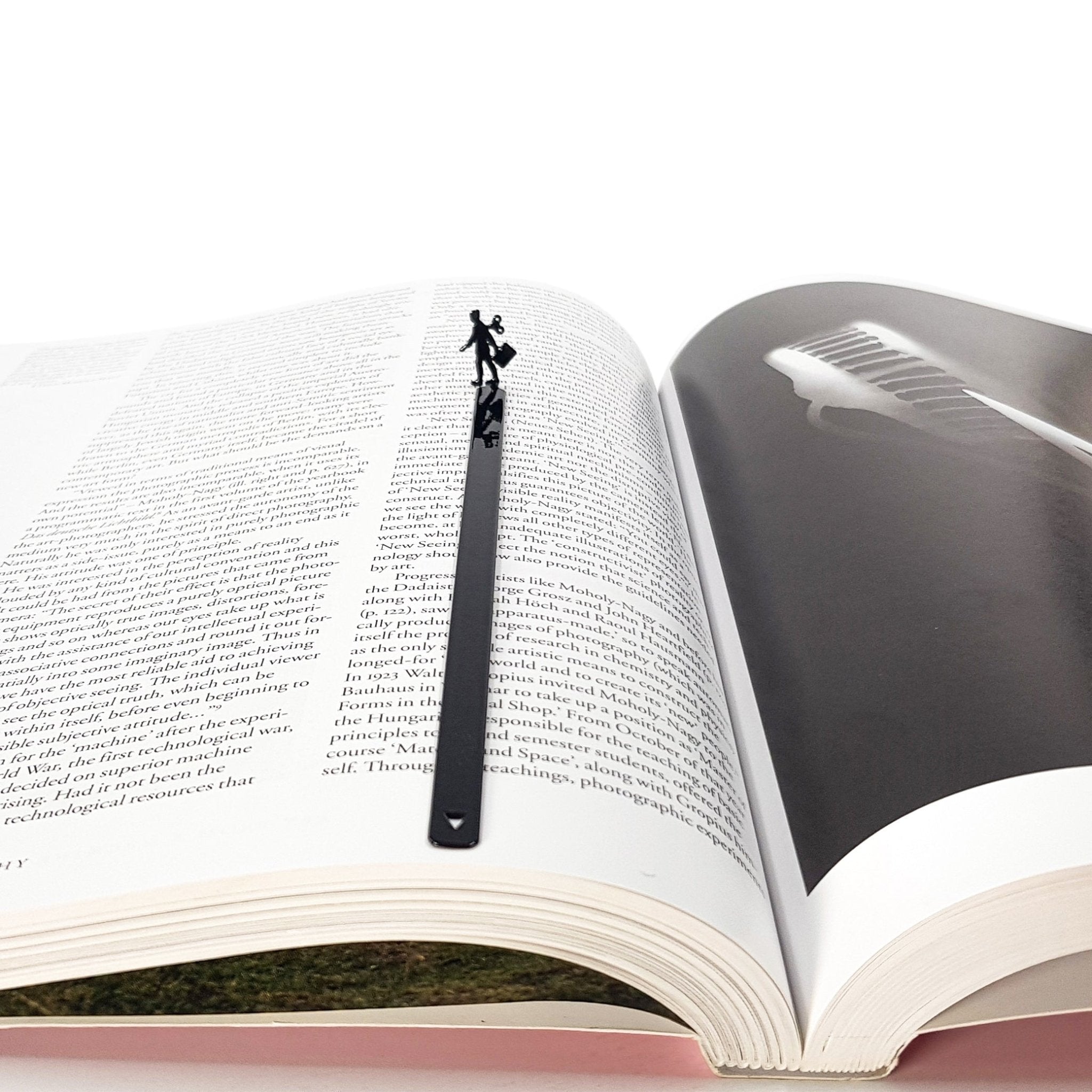 Black metal bookmark with a walking businesswoman silhouette centered in an open book, minimalist handmade reading accessory.