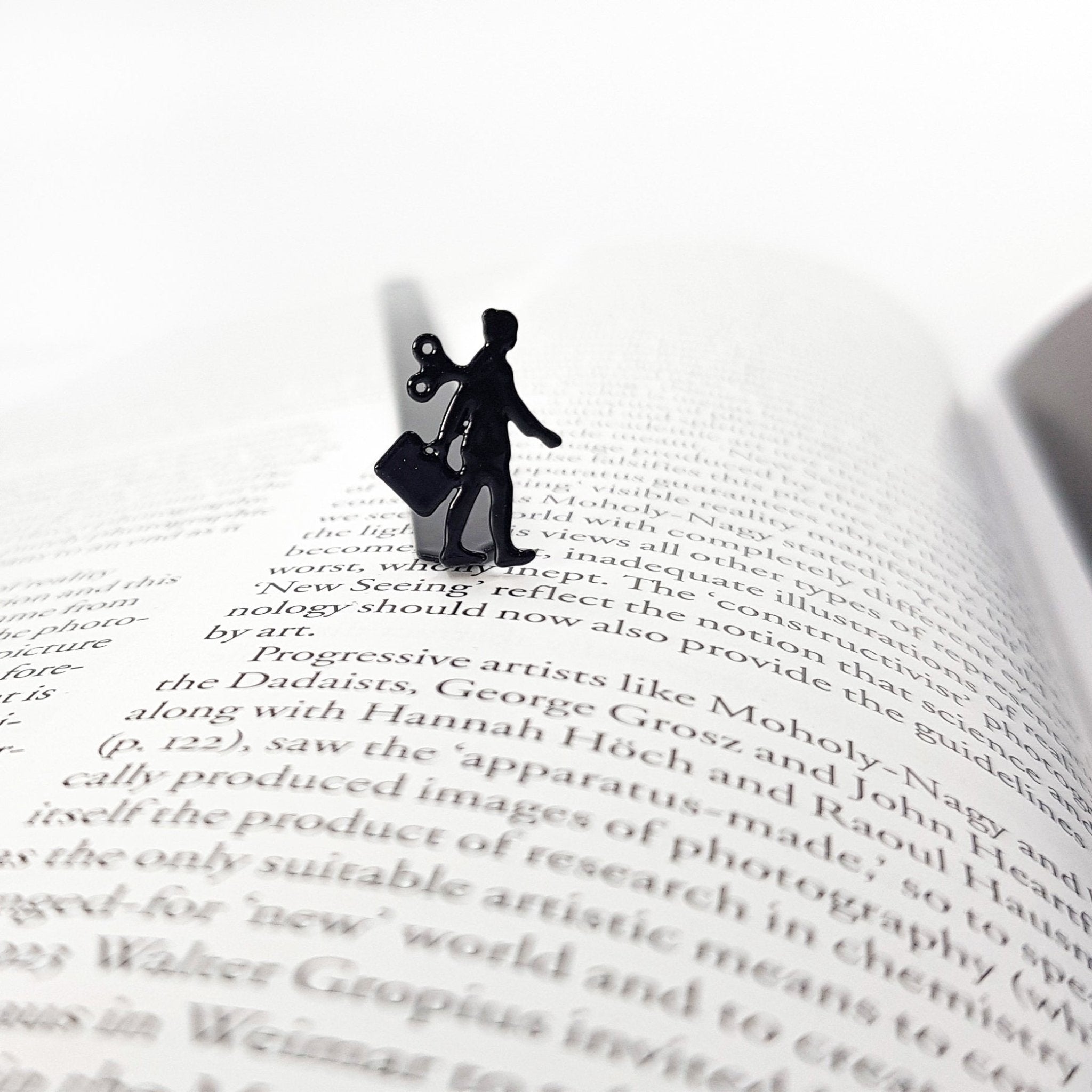 Black metal bookmark featuring a business woman silhouette resting on an open book page