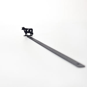 Full product shot — 17 cm laser-cut black steel cow bookmark on white background, diagonal view
