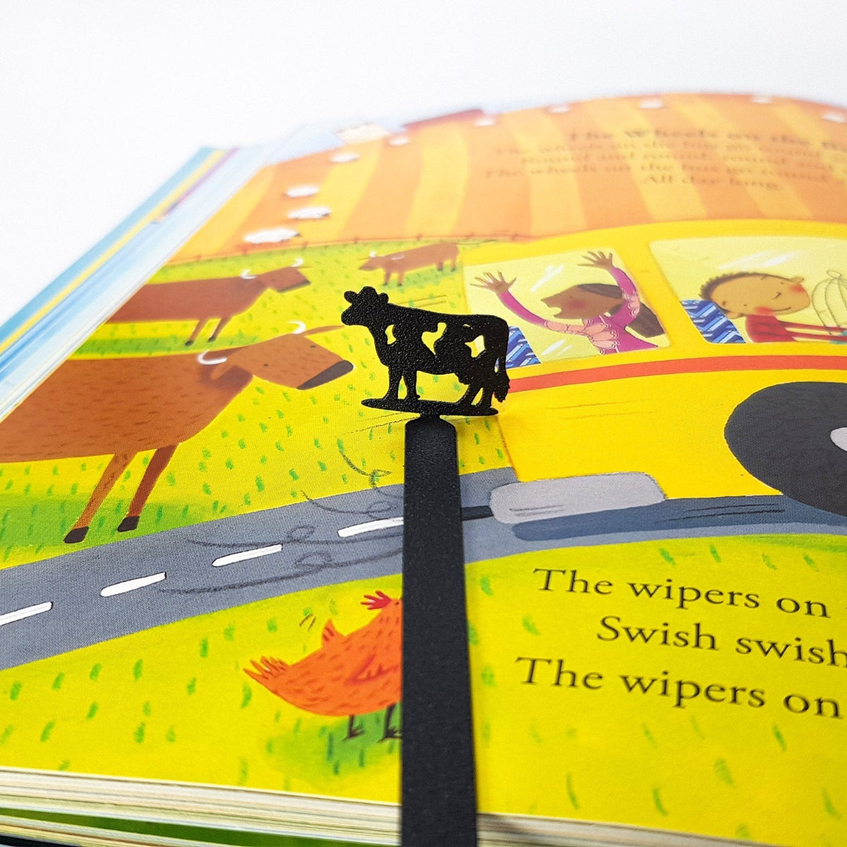 Metal Cow bookmark marking a page in an illustrated book