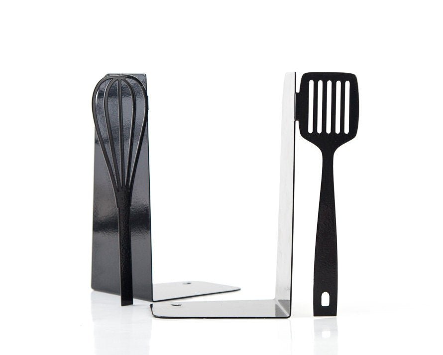 Black spatula and whisk cookbook bookends on a kitchen shelf
