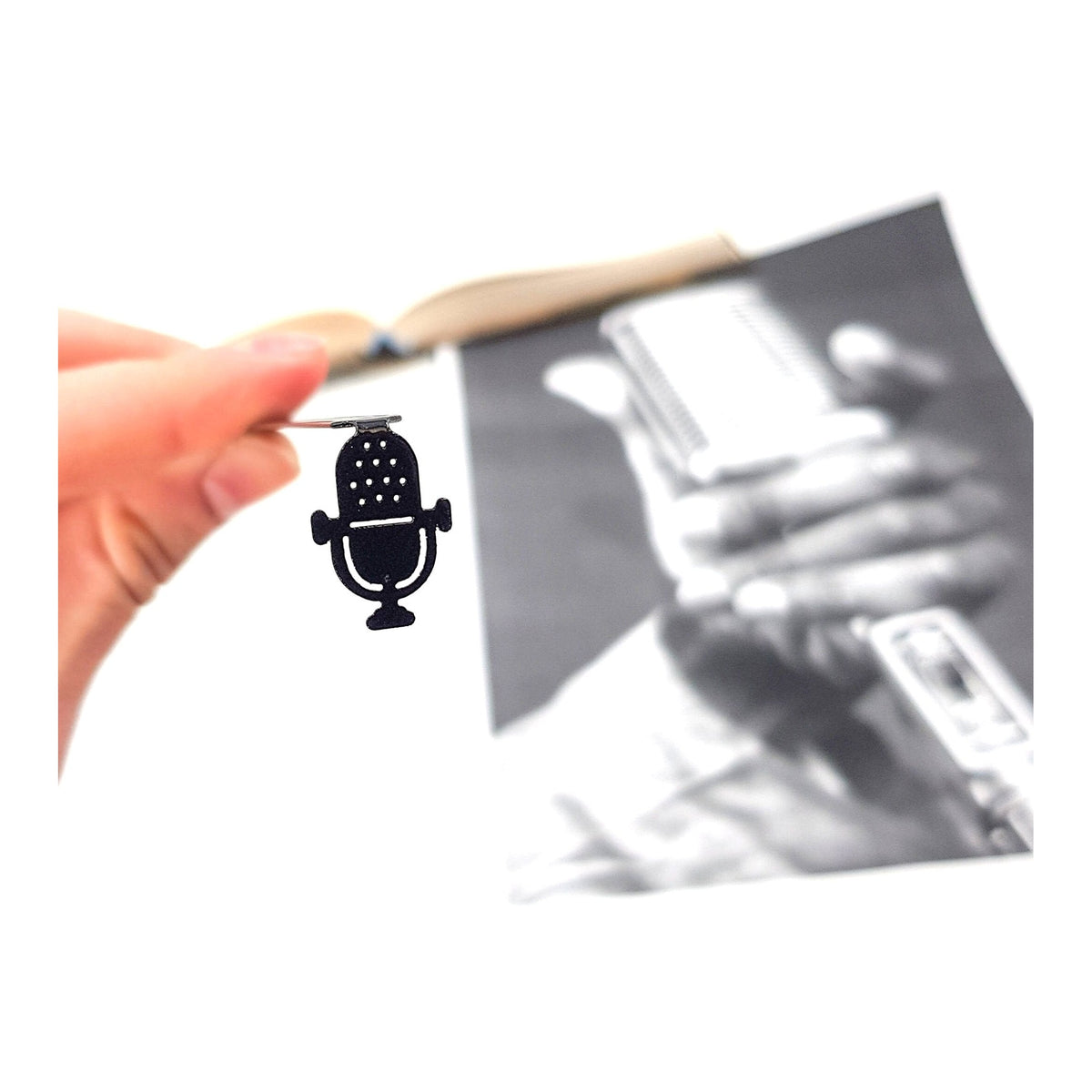 Microphone metal bookmark held in a hand above an open book