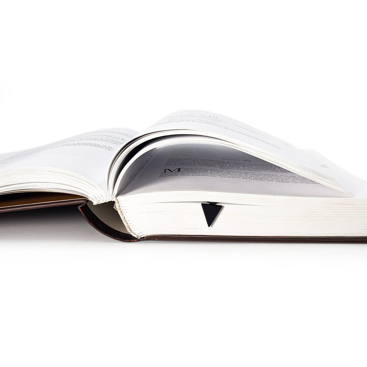 Minimalist Triangle metal bookmark resting on the pages of an open book