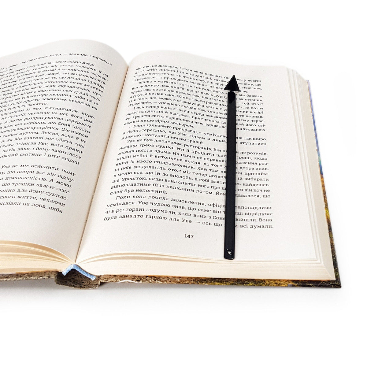 Minimalist Triangle metal bookmark marking a page in an open book