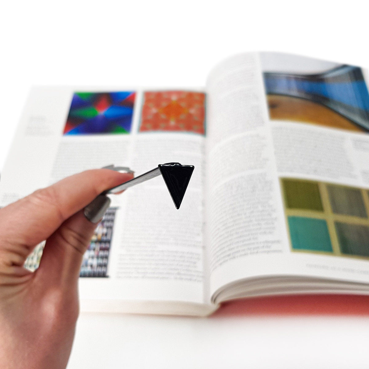 Minimalist Triangle metal bookmark marking a page in an illustrated book
