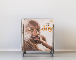 Front view of a minimalist steel vinyl record rack holding the album “Joy” by Isaac Hayes, with an open rectangular frame and clean industrial design.