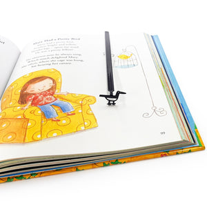 Minimalist black metal bird bookmark placed in a colorful illustrated book, shown vertically to highlight the long metal spine and bird silhouette.