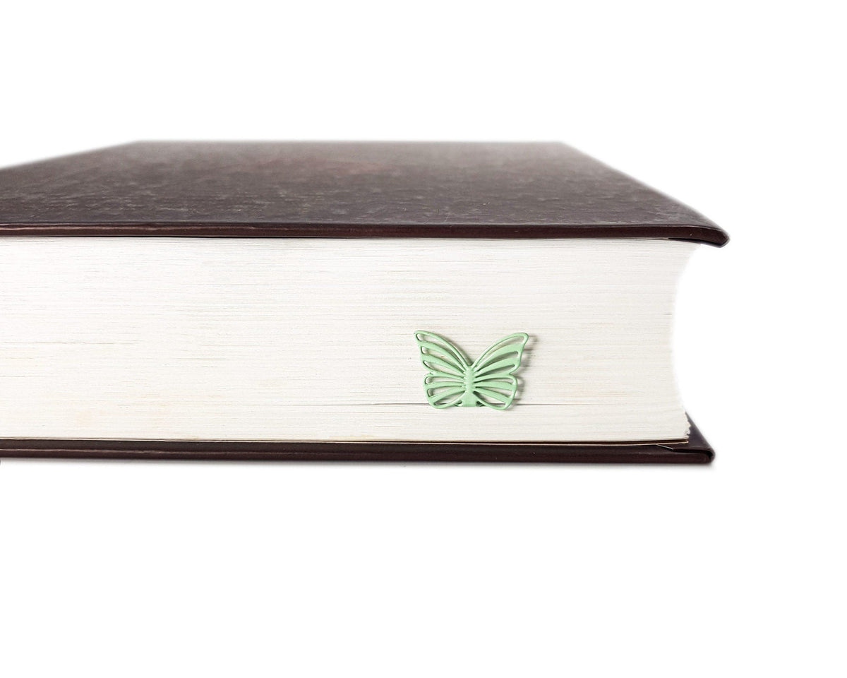 Mint Butterfly metal bookmark in green in a closed book, only its top showing above the pages