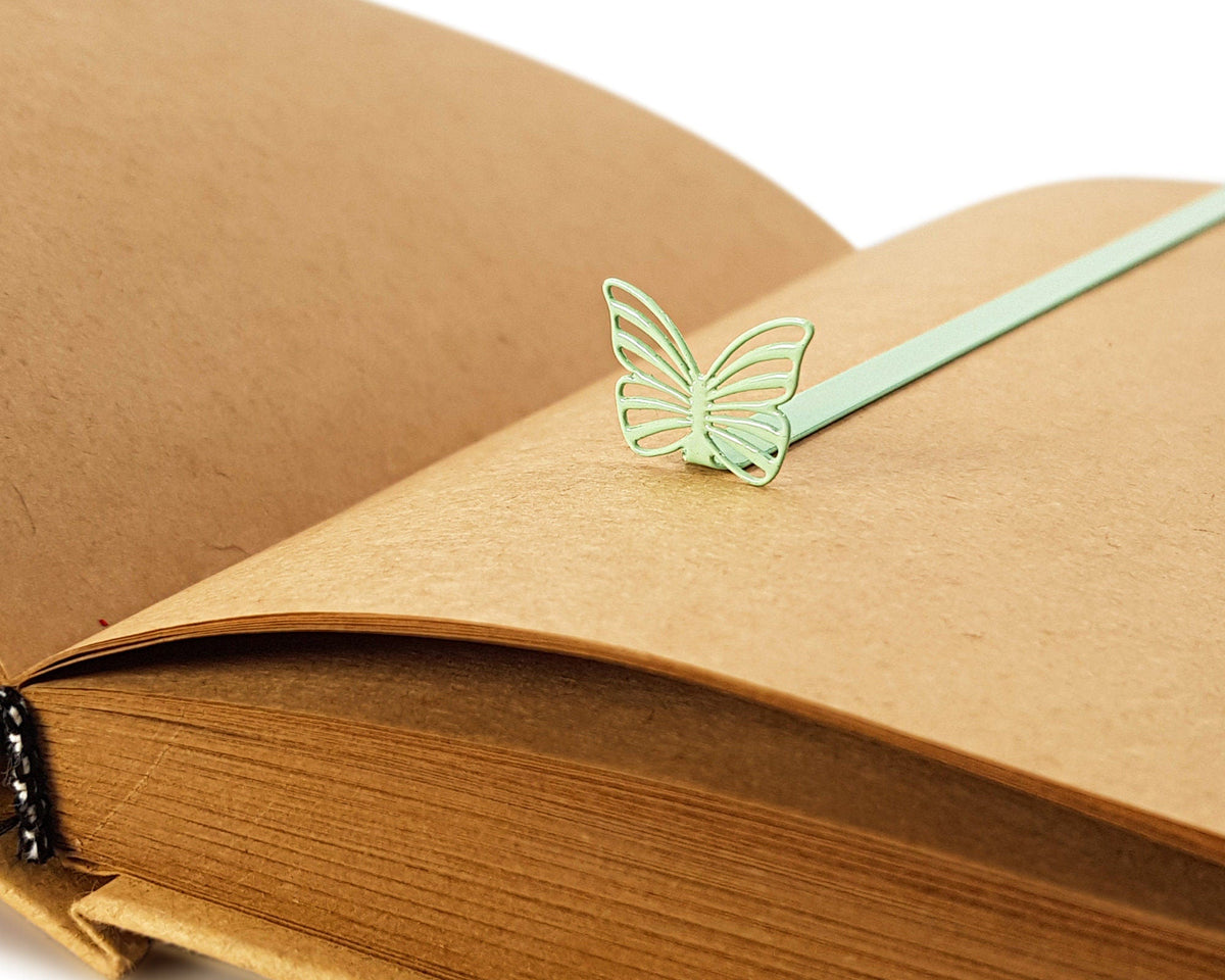Mint Butterfly metal bookmark in green marking a page in a notebook