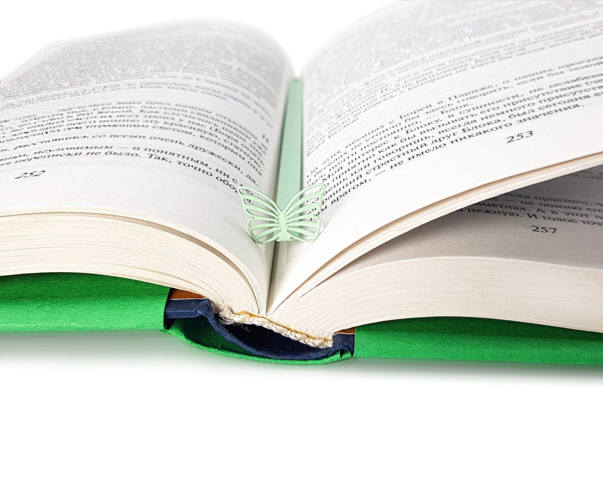Mint Butterfly metal bookmark in green marking a page in an open book