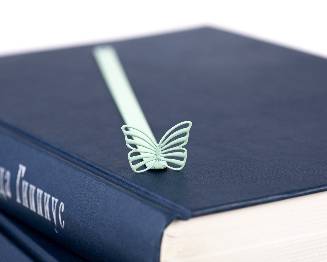 Mint Butterfly metal bookmark in green seen from the edge of a closed book