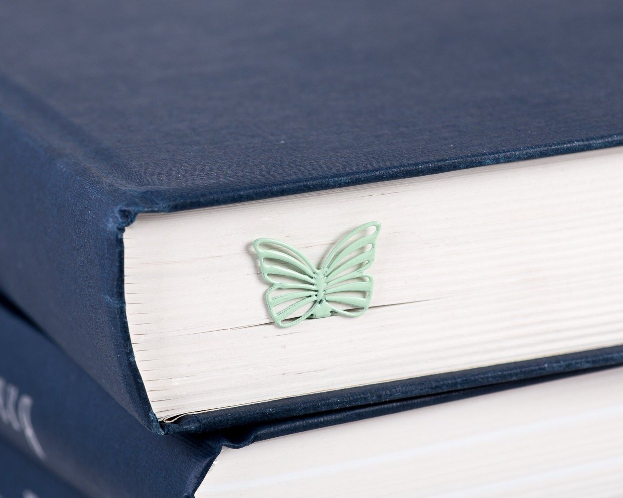 Mint Butterfly metal bookmark in green clipped in a closed book, viewed from the side