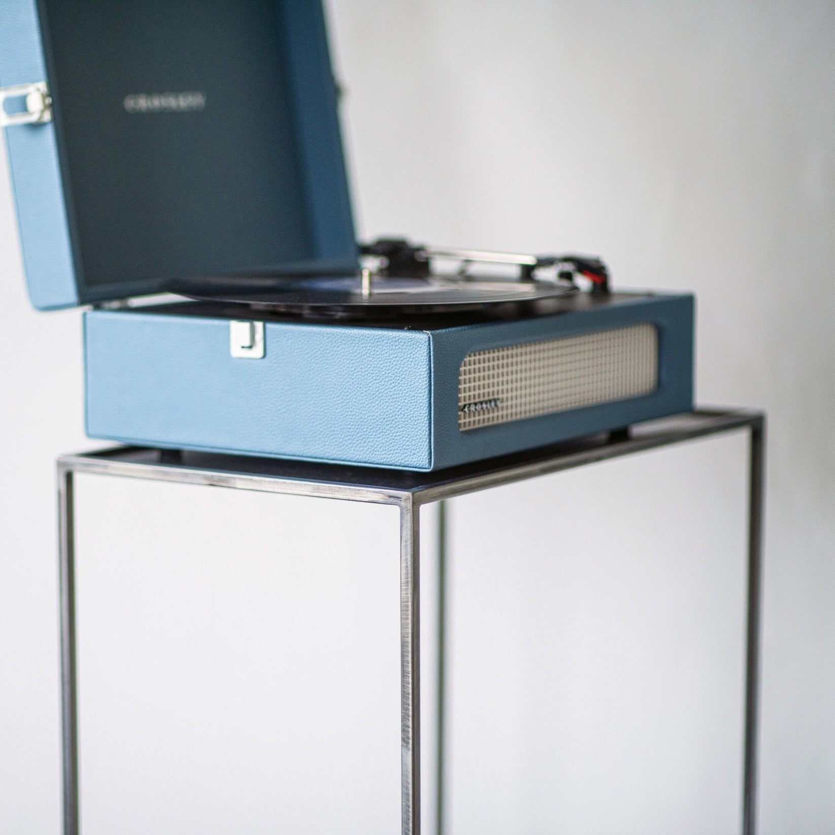 Close-up of a turntable resting on the raw steel top of the record player stand