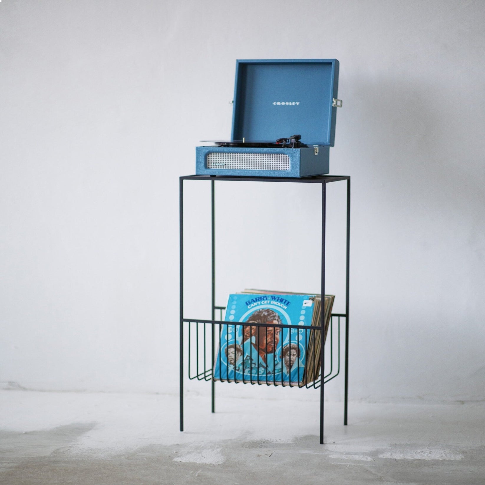 Black metal record player stand with turntable and open vinyl storage basket