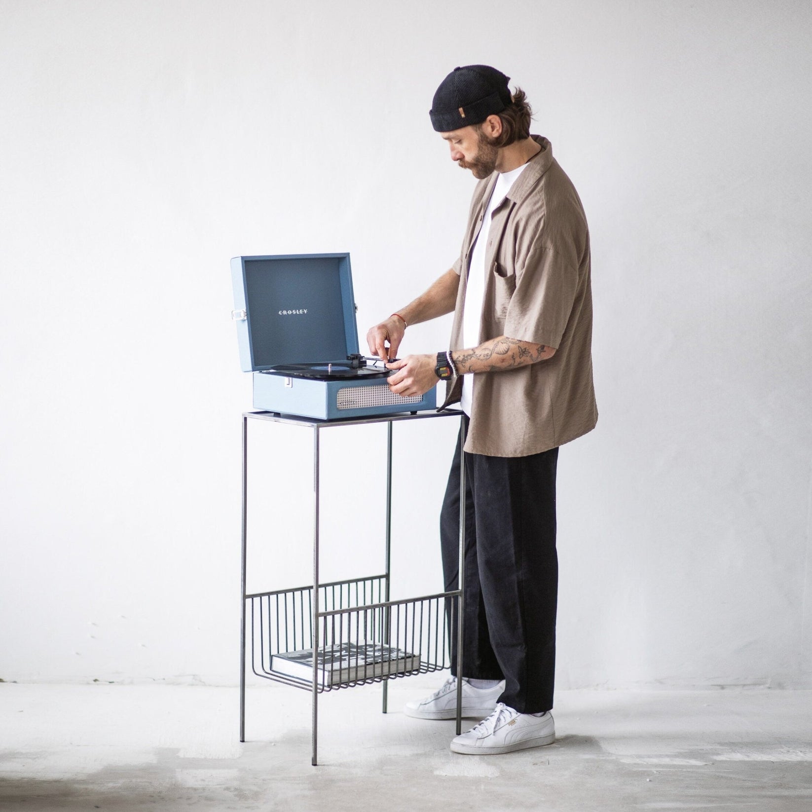 Person using a turntable on the full-height raw steel record player stand