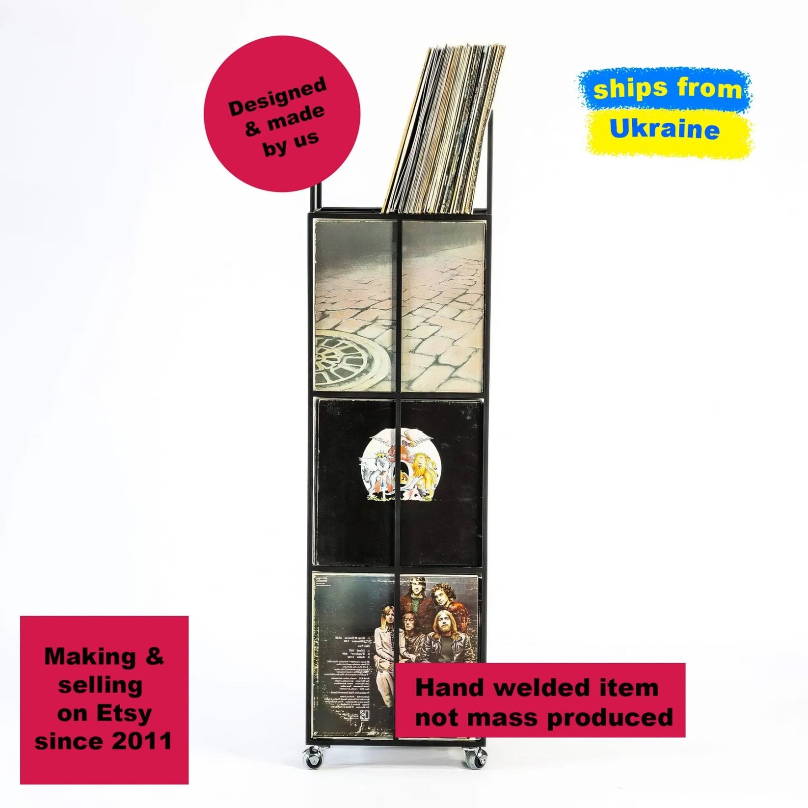 Tall four-tier black metal vinyl record stand on wheels, holding several LPs displayed vertically in four sections.