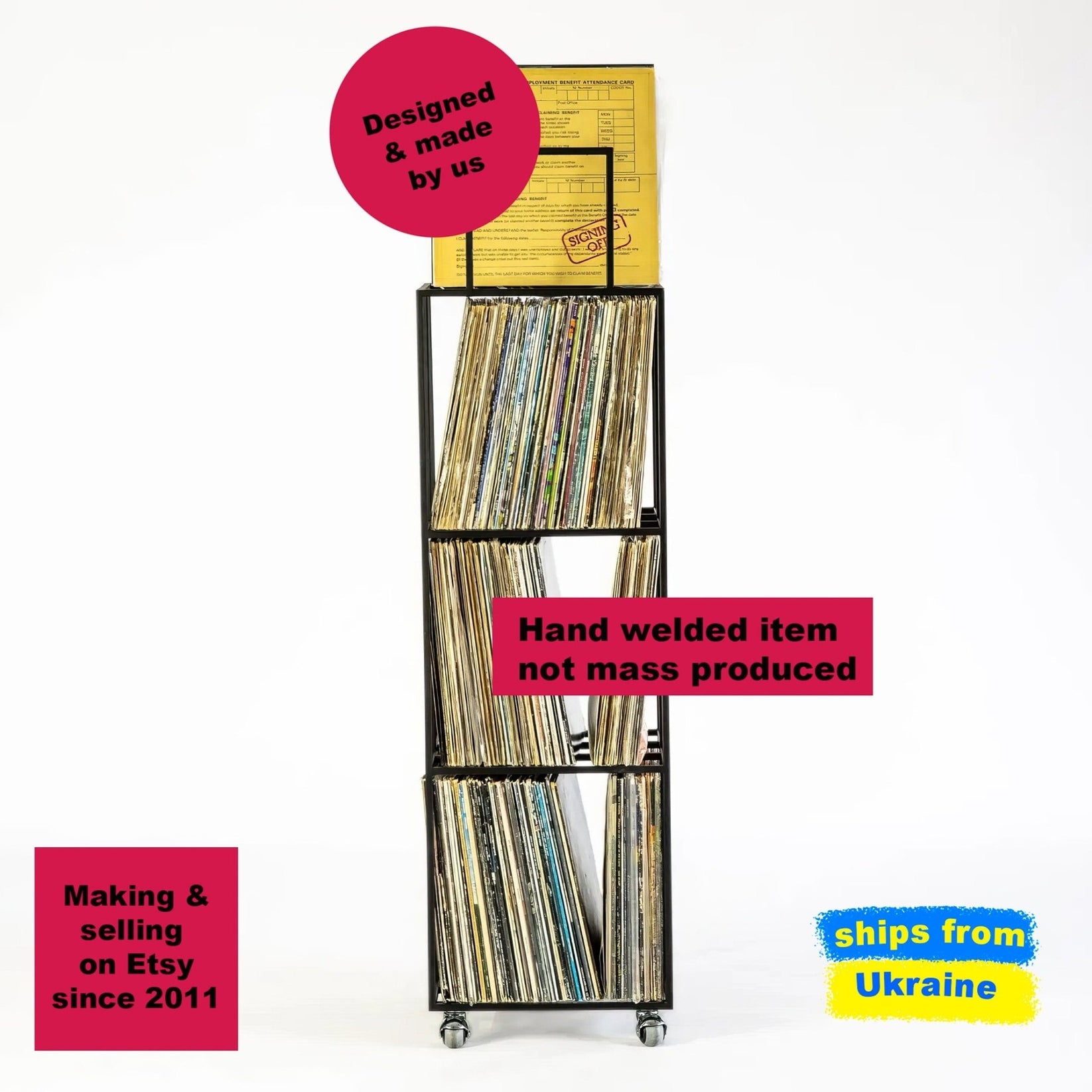 Tall black metal vinyl record rack on wheels with four compartments filled with LPs, including a yellow record on top. 