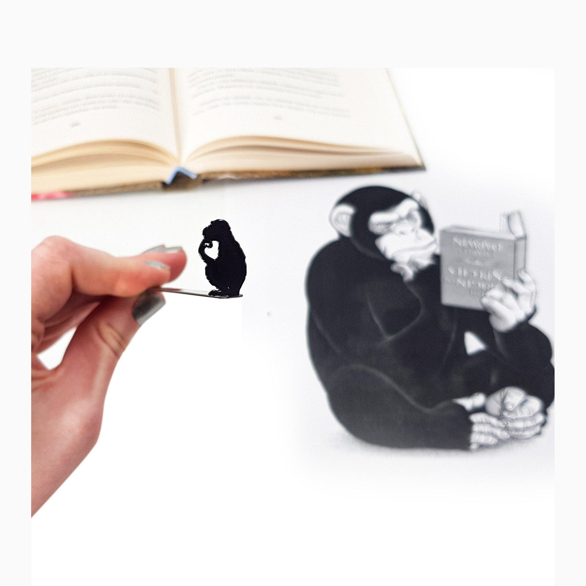 Monkey the Thinker metal bookmark marking a page in an illustrated book