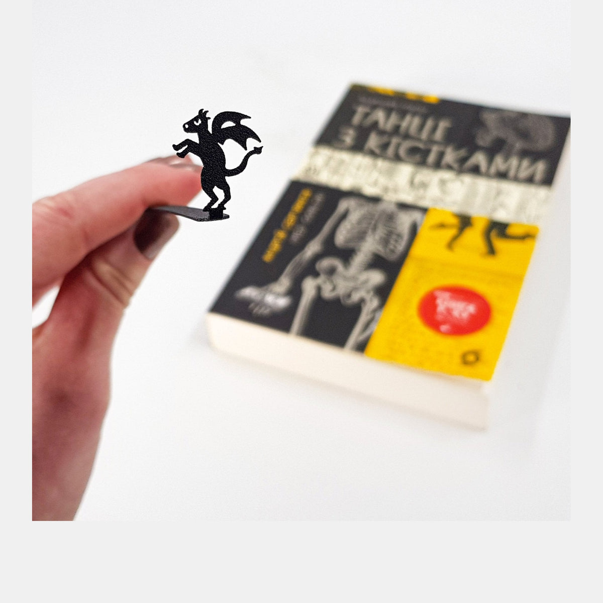 Monster Jersey Devil metal bookmark held in a hand above an open book