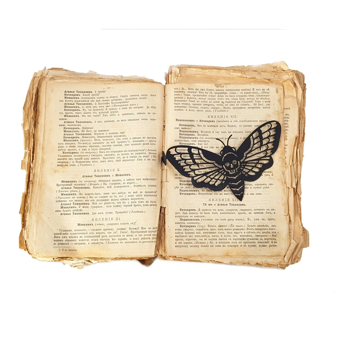 Moth of Death metal bookmark resting on the pages of an open book