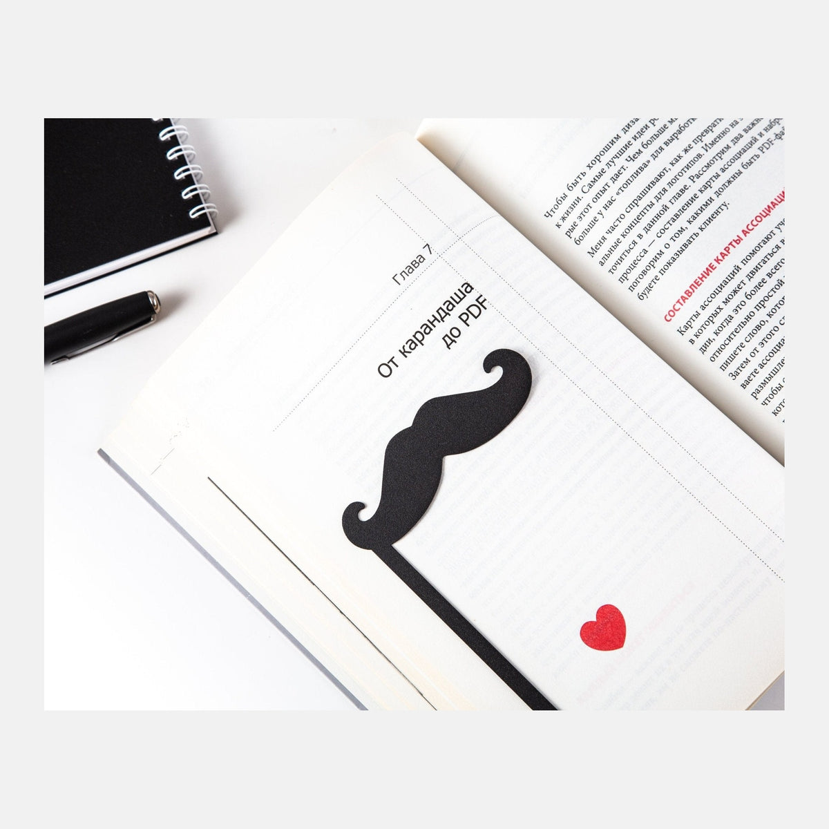Moustache metal bookmark resting on the pages of an open book