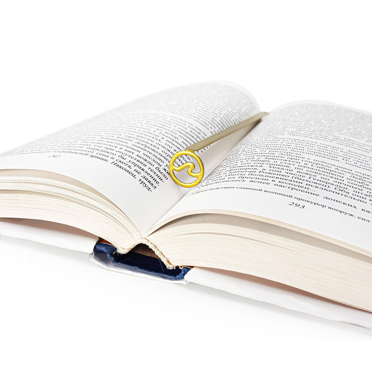 Nautical Big Wave metal bookmark in gold lying across the pages of an open book
