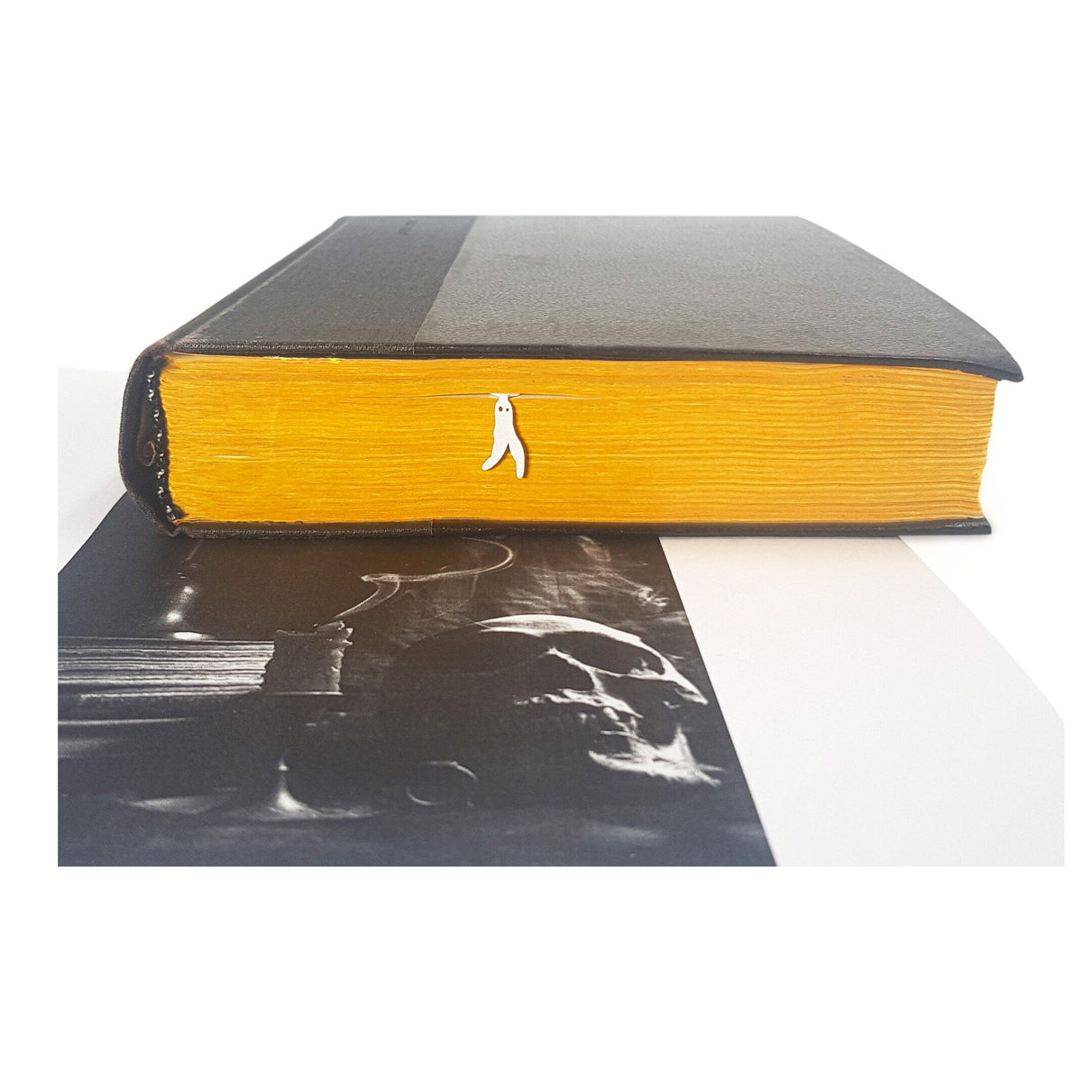 Nightcrawler metal bookmark in white in a closed book, only its top showing above the pages