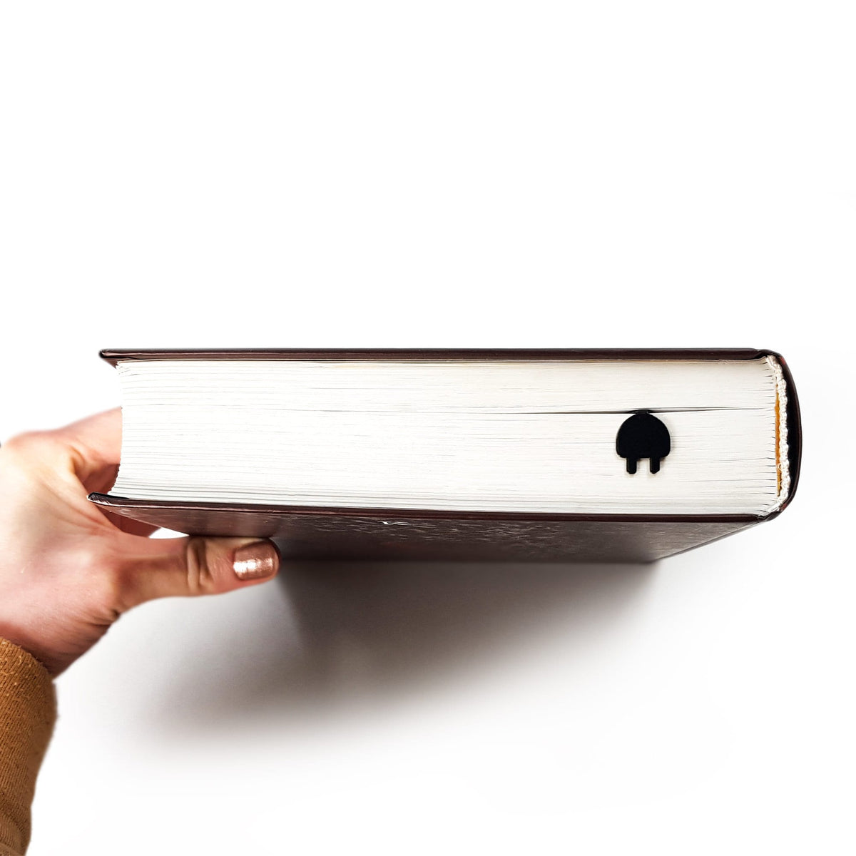 Electrical Plug metal bookmark in a closed book, only its top showing above the pages