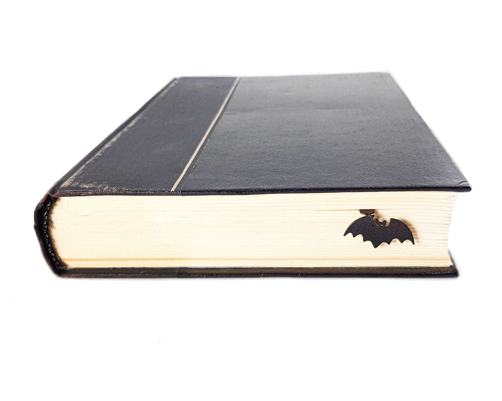 Kitti Bat metal bookmark seen from the edge of a closed book