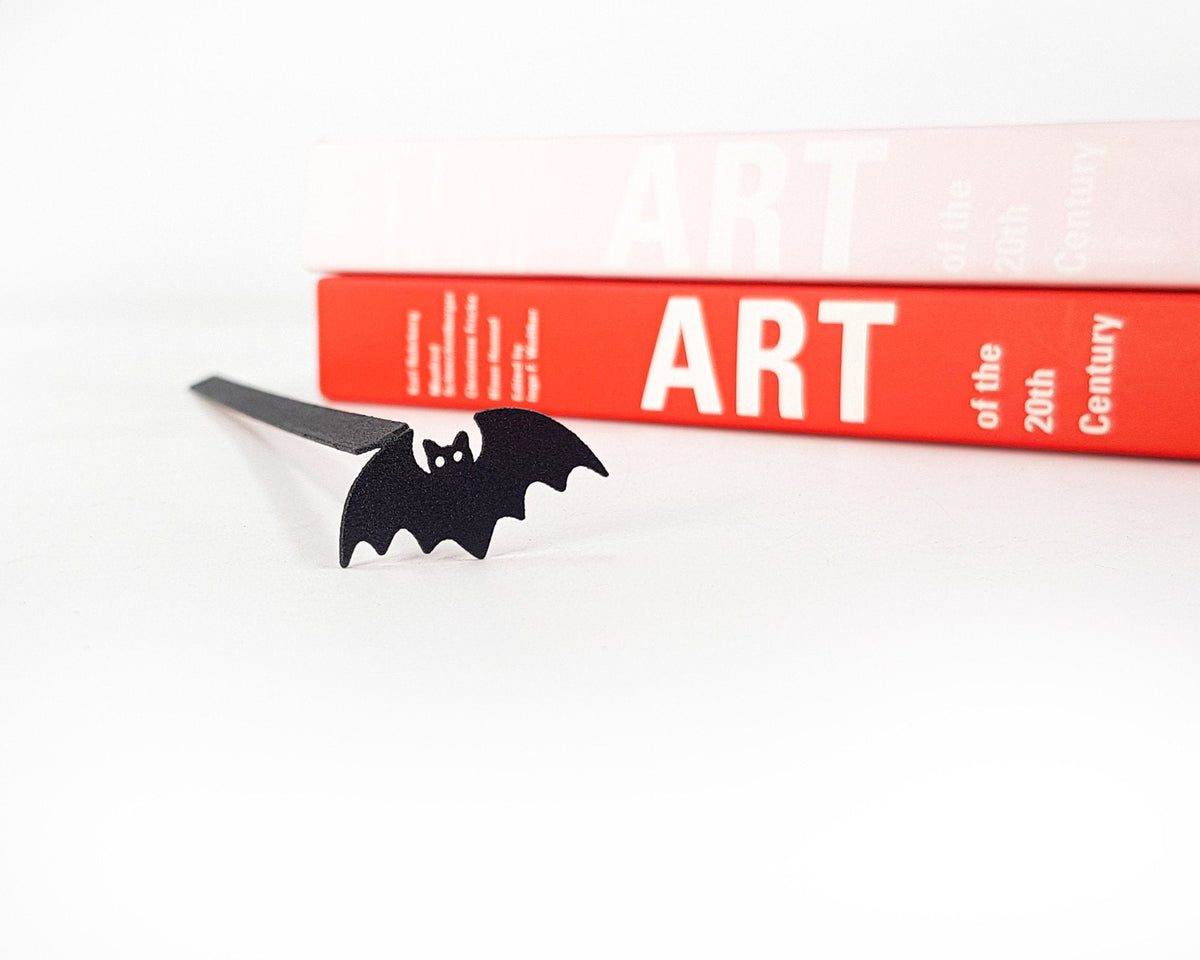 Kitti Bat metal bookmark in a closed book, only its top showing above the pages