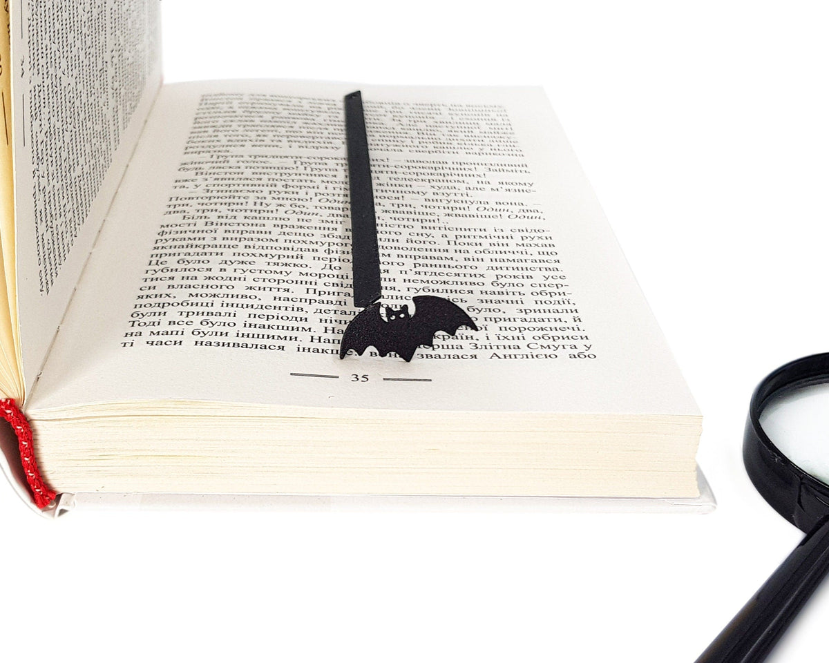 Kitti Bat metal bookmark resting on the pages of an open book