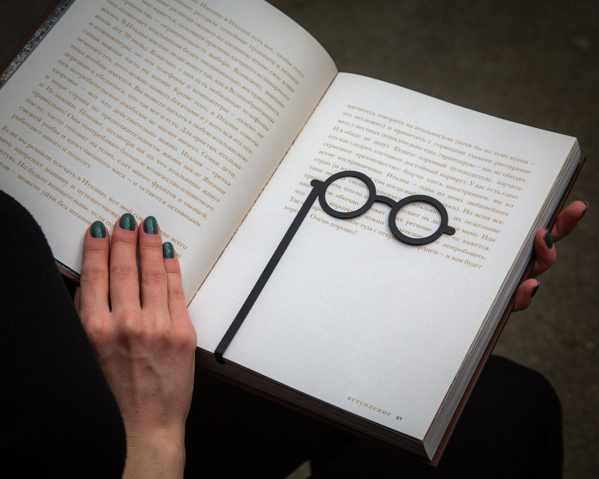 Lorgnettes metal bookmark held up beside an open book