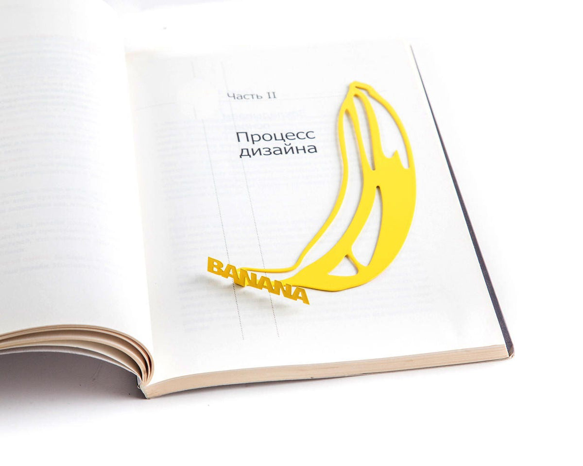 One Banana metal bookmark in gold resting on the pages of an open book
