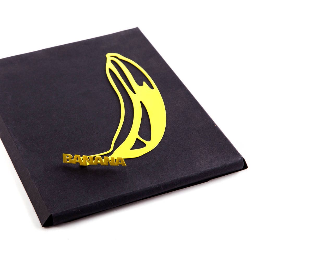 One Banana metal bookmark in gold tucked into a notebook