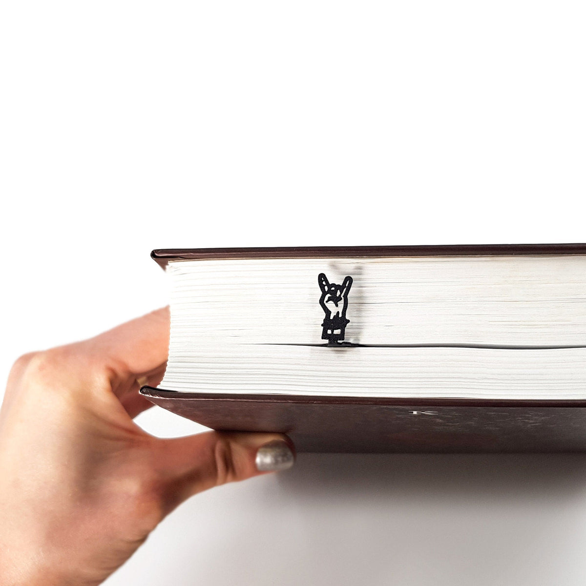 Rock and Roll metal bookmark held up beside an open book