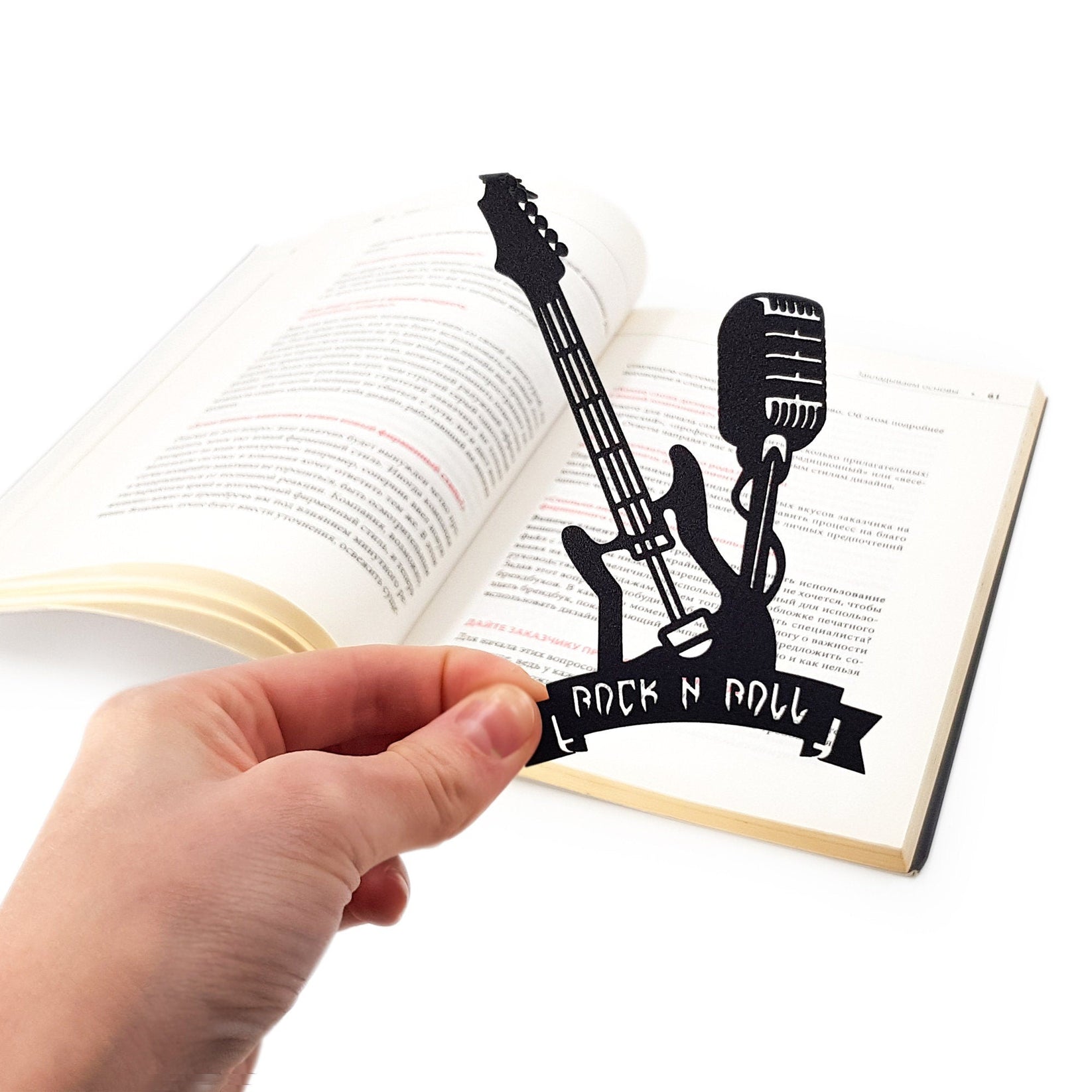 Rock and Roll metal bookmark held in a hand above an open book