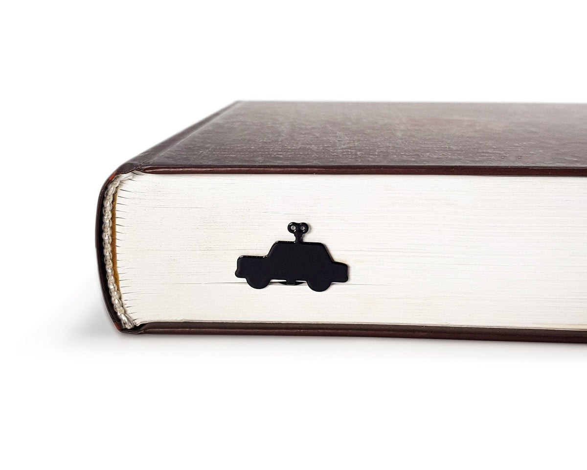 Wind-Up Toy Car metal bookmark in a closed book, only its top showing above the pages