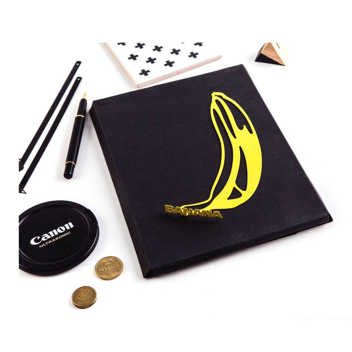 One Banana metal bookmark in gold marking a page in a notebook