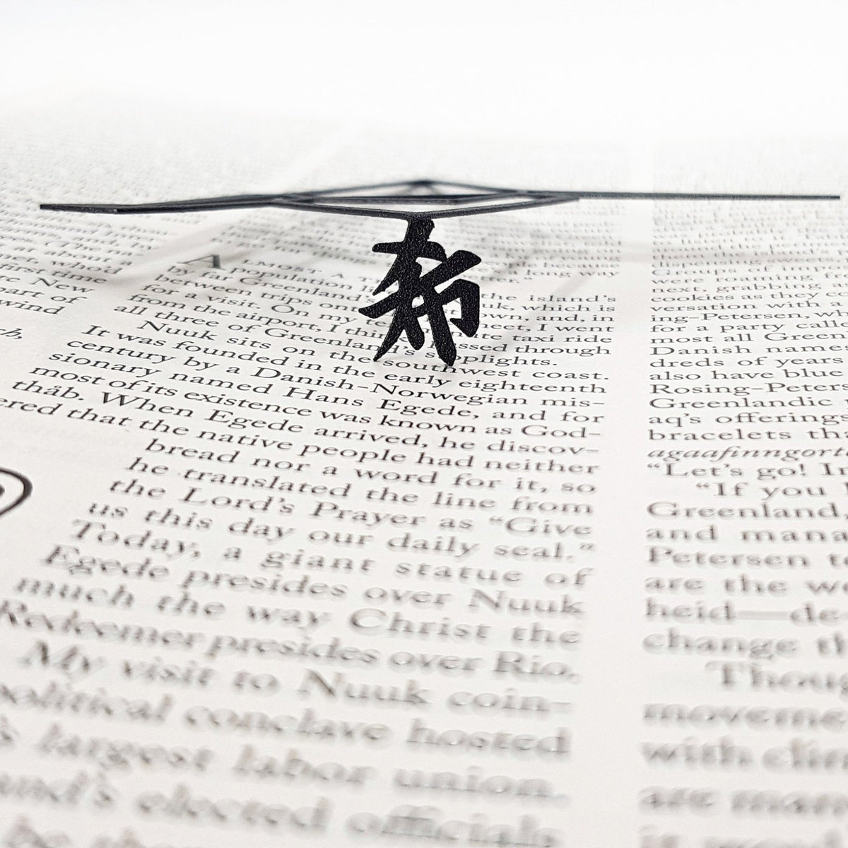 Origami Crane metal bookmark resting on the pages of an open book